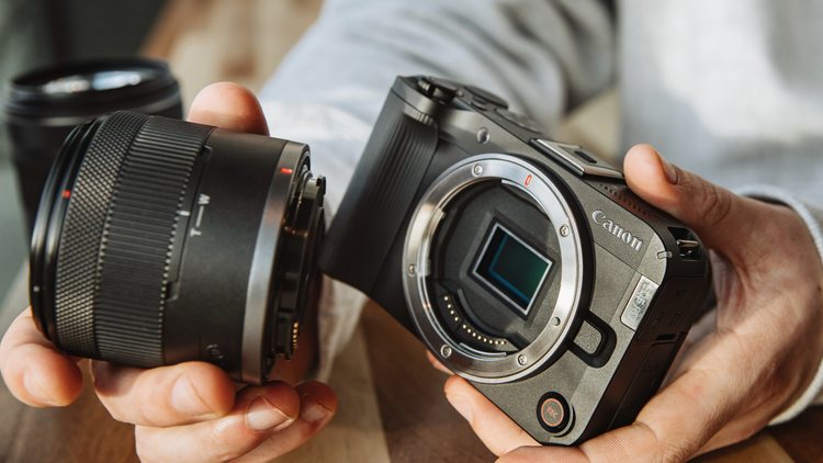 Canon EOS R50 V и снятый объектив в руках