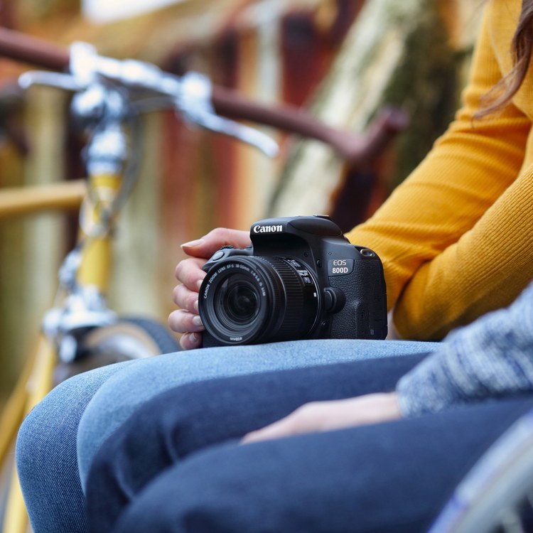 Canon EOS 800D с объективом 18–55 мм в руках фотографа